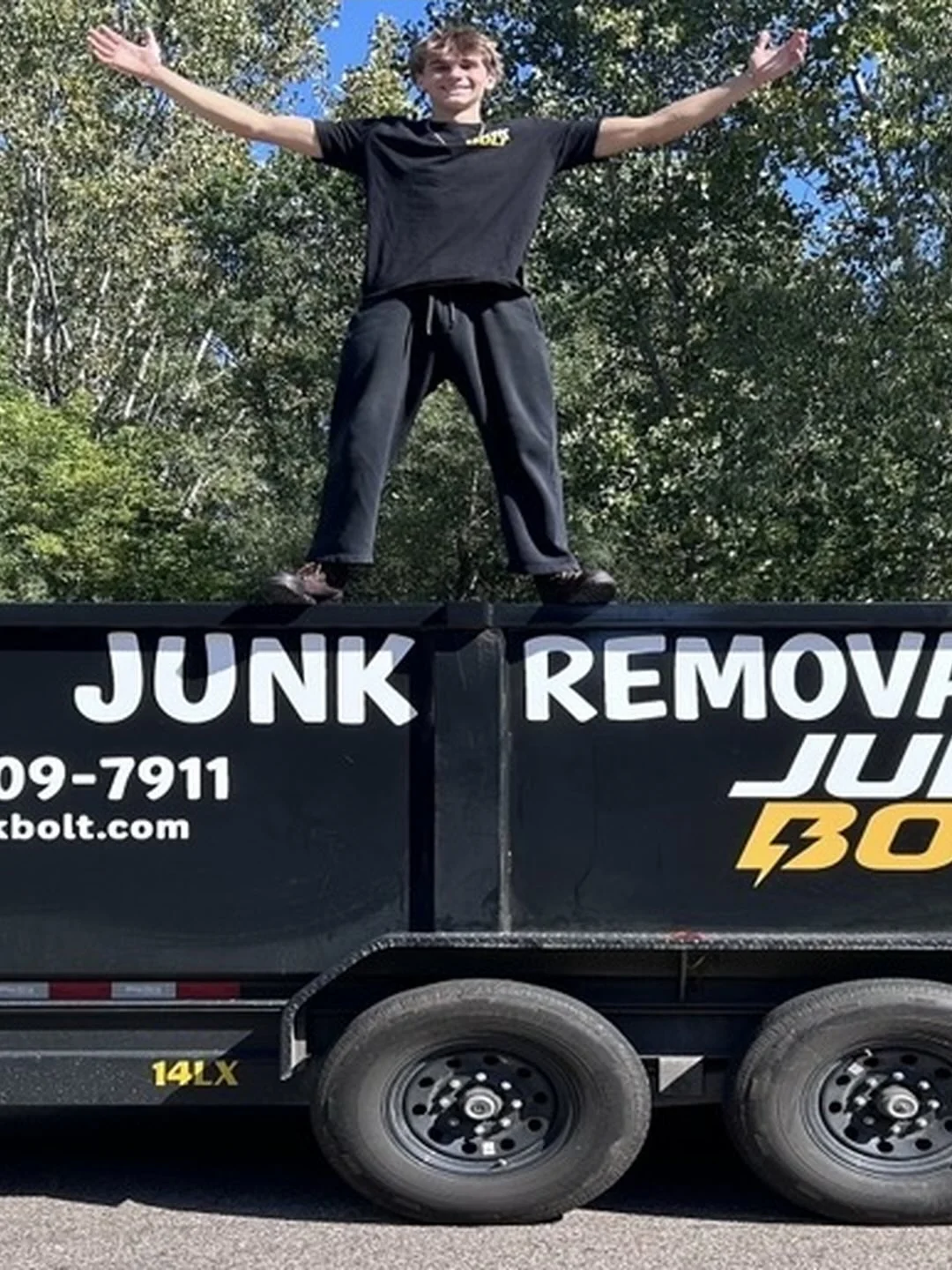 Booker, the owner of Junk Bolt, standing on his branded junk-removal trailer.